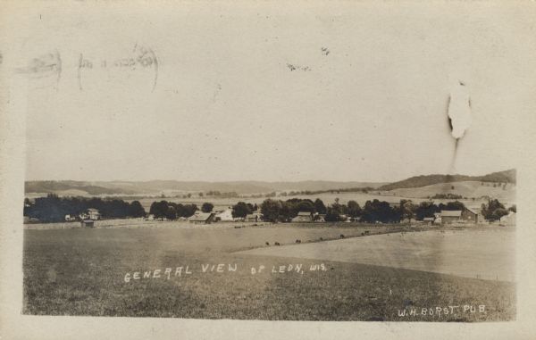 Elevated view across fields towards a small town. Caption reads: "General View of Leon, Wis."