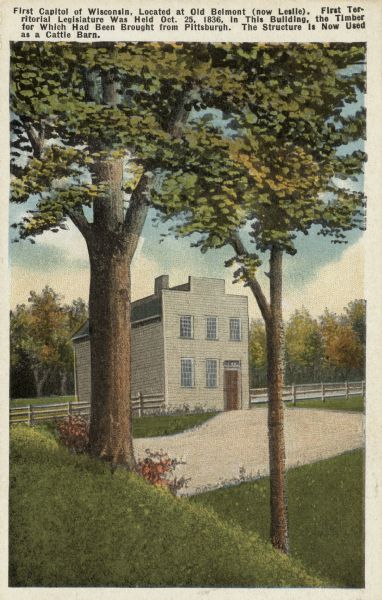 Illustrated postcard of the first Capitol. Text on front reads: "First Capitol of Wisconsin, Located at Old Belmont (now Leslie). First Territorial Legislature Was Held Oct. 25, 1836. In this building, the Timber for Which Had Been Brought from Pittsburgh. The Structure is Now Used as a Cattle Barn."