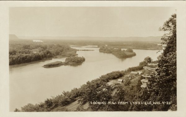 Elevated view of the Mississippi River at Lynxville. Railroad tracks are running alongside the shoreline. Caption reads: "Looking N.W. from Lynxville, Wis."