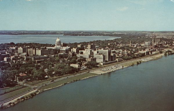 Aerial view of the Isthmus from over Lake Monona. The Wisconsin State Capitol and Lake Mendota are in the background. In the foreground is John Nolen Drive along the north and west shoreline of Lake Monona.