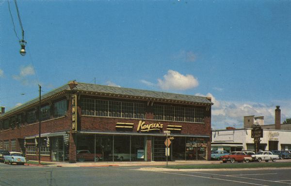 View across street towards Kayser Motors located at 702-716 East Washington Avenue (at Blount Street). Automobiles are parked at the curbs and inside the showroom.