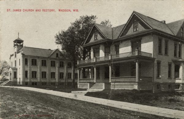 Exterior view across unpaved road towards a two-story church on the left, and a rectory on the right. Caption Reads: "St. James Church and Rectory, Madison, Wis."
