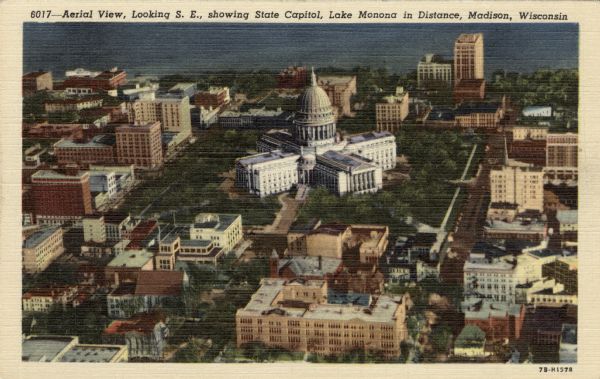 Aerial view of Capitol Square from over Wisconsin Avenue. MATC Downtown in the foreground. Caption reads: "Aerial Vew, Looking S.E., showing State Capitol, Lake Monona in Distance, Madison, Wis."