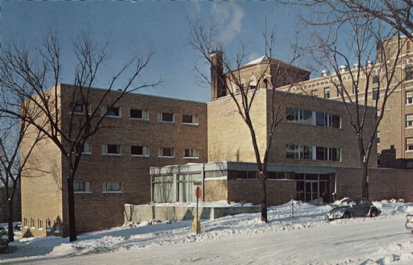 Color postcard of Jackson Clinic, 30 South Henry Street in winter. Automobiles are parked at the curbs.