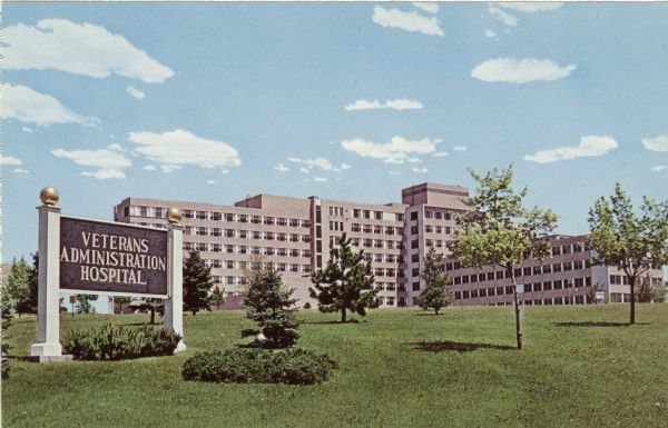 Exterior view of a VA Hospital from across a lawn with small trees.