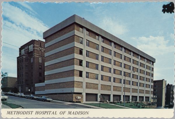 View across street towards the Methodist Hospital at 309 W. Washington Avenue. Automobiles are parked along the curb. Caption reads: "Methodist Hospital of Madison, Madison, Wis."