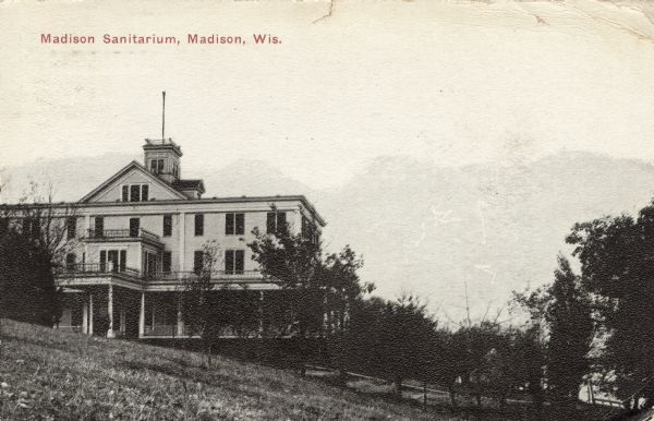 Exterior view of a hospital building on a hill. Caption reads: "Madison Sanitarium, Madison, Wis."