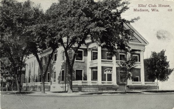 Exterior view of the clubhouse on a street corner surrounded by trees. Caption reads: "Elks' Club House, Madison, Wis."