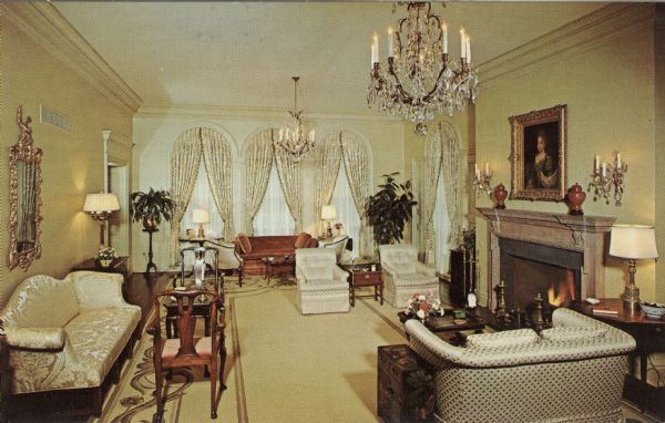 Interior of the drawing room at the Governor's Mansion. The room is furnished with antique furniture, draperies and chandeliers. A woman's portrait is hanging above the fireplace.