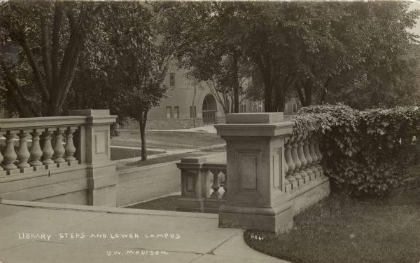 View of the steps of the Langdon Street entrance to the Historical Society building. The armory (red gym) is across the street in the background. Caption reads: Library Steps and Lower Campus, U.W. Madison."