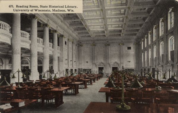 Interior view of the State Historical Society reading room on the second floor. Long wooden tables are on either side of the room. Caption reads: "Reading Room, State Historical Library, University of Wisconsin, Madison, Wis."