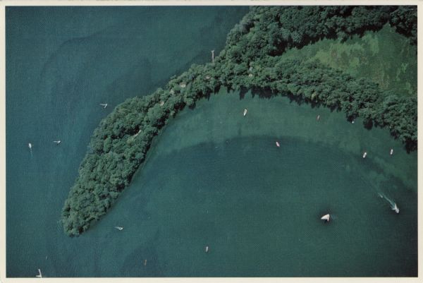 Aerial shot directly over Picnic Point. Boats are in the lake. Text on reverse reads: "Picnic Point — A peninsula of the University of Wisconsin campus jutting nearly nearly 3/4 mile into Lake Mendota. It serves as a natural park containing foot trails, picnic sites and a swimming beach."