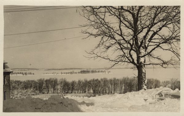 A sepia-toned photographic postcard of Picnic Point as seen from Observatory Drive. The lake is frozen and snow is on the ground.