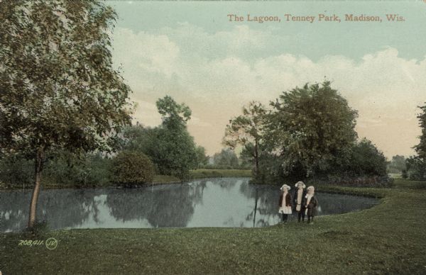 View of the lagoon at Tenney Park, with three girls standing together near the shoreline. Caption reads: "The Lagoon, Tenney Park, Madison, Wis."