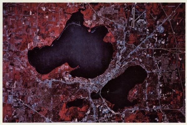 Text on reverse reads: "Madison, Wisconsin photographed on infrared film at an altitude of 22 miles from a NASA research aircraft.
Red = vegetation
Blue = water"