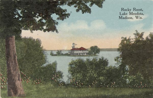 View from shoreline of Rocky Roost, a Frank Lloyd Wright-designed cottage on an island in Lake Mendota. A windmill is behind the cottage. Caption reads: "Rocky Roost, Lake Mendota, Madison, Wis."