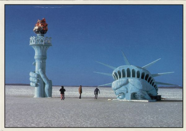 View of the forehead and torch of a replica of the Statue of Liberty installed by the Pail and Shovel Party on the snow-covered ice of Lake Mendota. Text on reverse reads:"A campaign promise to 'Bring the Statue of Liberty to Madison', made during the election of 1978 for Wisconsin Student Association offices at the University of Wisconsin, was fulfilled without delay upon victory and the Statue was first erected on Lake Mendota in February 1979."
