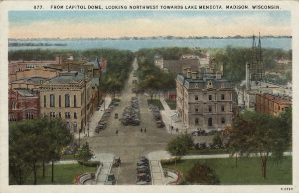 Elevated view of Wisconsin Avenue from Capitol Square to Lake Mendota. City Hall is on the left. Radio towers are on a rooftop on the right. Caption reads: "From Capitol Dome, Looking Northwest Towards Lake Mendota, Madison, Wis."