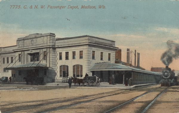 View across railroad tracks towards the railroad depot. A train is approaching on the right. A horse and carriage are in front of the roofed platform. Caption reads: "C. & N. W. Passenger Depot, Madison, Wis."