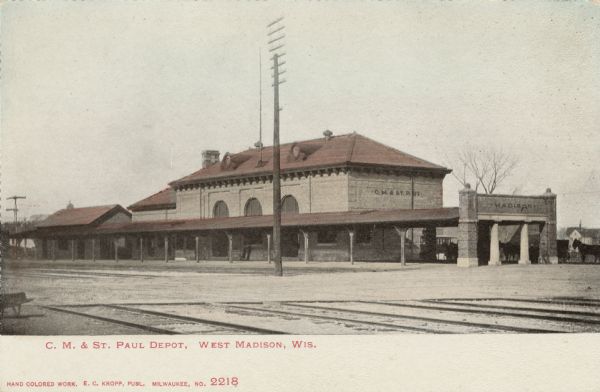 View across railroad tracks towards the depot and railroad yard of the C.M. and St. Paul railroad. Caption reads: "C. M. & St. Paul Depot, West Madison, Wis."
