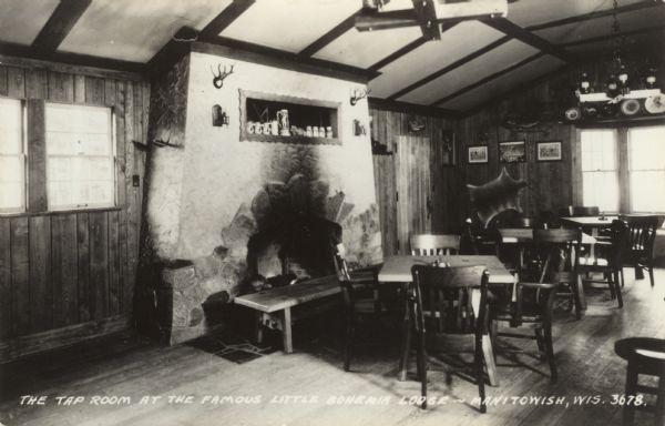 Interior view of the tap room, with tables and chairs, and a bench in front of the large fireplace. Beer steins are on a shelf above the fireplace. Caption reads: "The Tap Room at the Famous Little Bohemia Lodge — Manitowish, Wis."