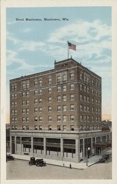 Elevated view of an eight-story hotel on a downtown corner. Automobiles are parked along the curb. Caption reads: "Hotel Manitowoc, Manitowoc, Wis."