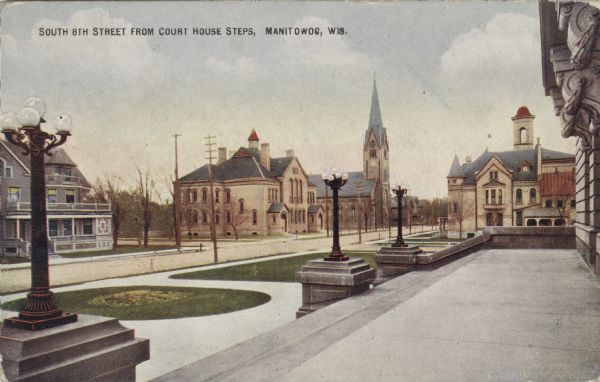View of 8th Street and a church from the entrance of the courthouse. Caption reads: "South 8th Street from Court House Steps, Manitowoc, Wis."