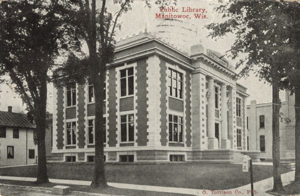 Exterior view of the Manitowoc Public Library, a brick and stone building with columns at the entrance. Caption reads: "Public Library, Manitowoc, Wis."