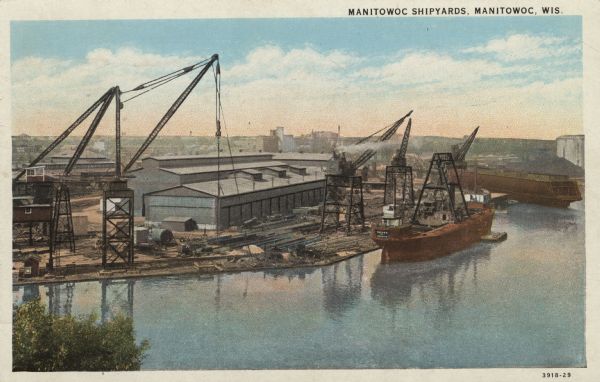 Elevated view of the Manitowoc shipyards on Lake Michigan. Two ships are being built. Caption reads: "Manitowoc Shipyards, Manitowoc, Wis."