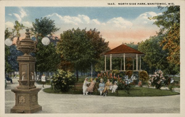 View of a park with a gazebo. Women and children are sitting on the benches. Caption reads: "North Side Park, Manitowoc, Wis."