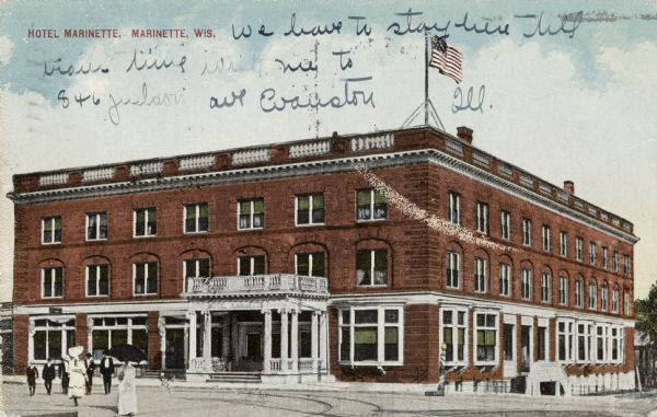 Exterior view of the Hotel Marinette. There is a barber pole on the corner, and pedestrians are in the street. Caption reads: "Hotel Marinette, Marinette, Wis."