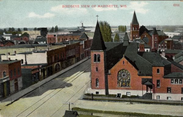 Elevated view of a commercial street. There are church buildings on the right. Caption reads: "Birdseye [sic] View of Marinette, Wis."