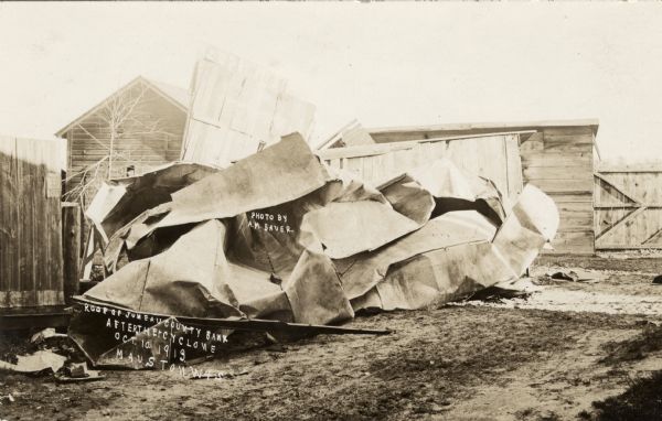 View of the blown-off roof of a bank. Caption reads: "Roof of Juneau County Bank after the Cyclone, Oct. 10, 1913, Mauston, Wis."