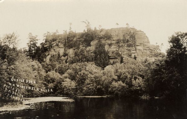 View across water towards the bluff on the river. Caption reads: "Castle Rock on Wisconsin River, Mauston, Wis."