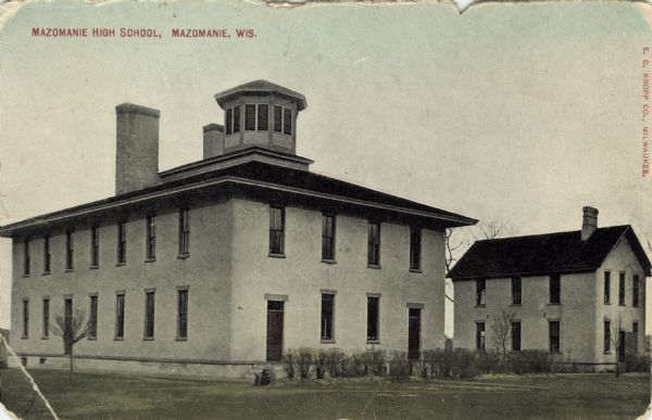 Exterior view of a high school building with a bell tower in the center of the roof. Caption reads: "Mazomanie High School, Mazomanie, Wis."