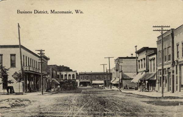 View down center of a street in Mazomanie. Horse-drawn vehicles are hitched along the curb. Caption reads: "Business District, Mazomanie, Wis."