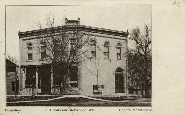 Exterior view from street towards a building on a corner. Caption reads: "Postoffice, J.S. Johnson, McFarland, Wis., General Merchandise."