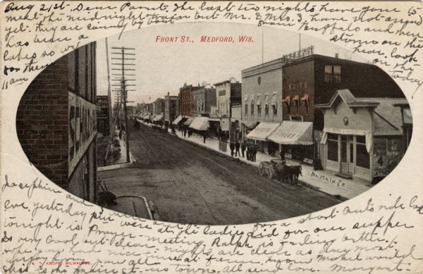 Elevated view of a city street lined with businesses. A horse and wagon are at the curb. Caption reads: "Front St., Medford, Wis."