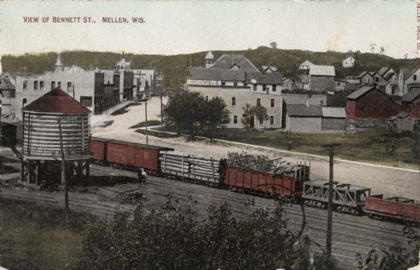 Elevated view of central Mellen from across the railroad yard. A freight train with logs is on the tracks.