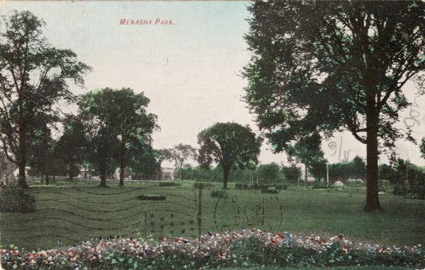 View of Menasha Park with a flower bed in the foreground. Caption reads: "Menasha Park."