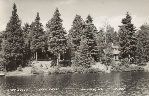 View across lake towards cottages on the shoreline surrounded by pine trees. A rowboat and canoe are on the shore. Caption reads: "Echo Lodge, Echo Lake, Mercer, Wis."