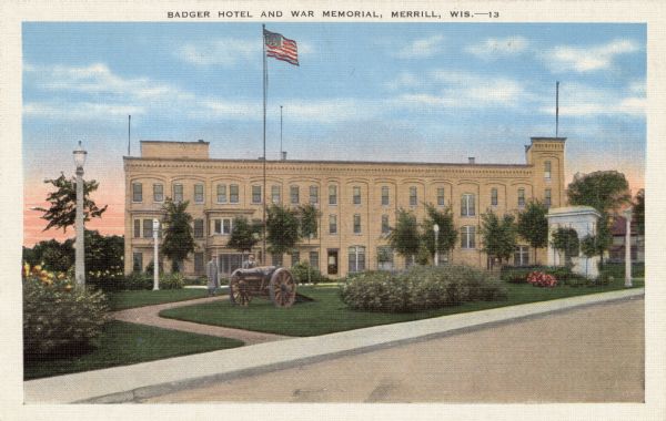 View from street towards a park with a cannon, a flagpole, lampposts and an arch. Two men are standing on the curved walk of the park. In the background is a hotel. Caption reads: "Badger Hotel and War Memorial, Merrill, Wis."