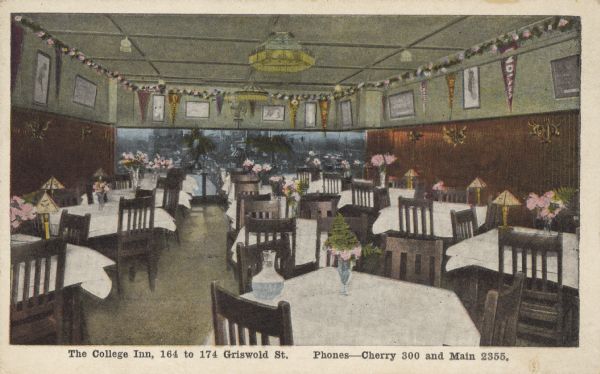 Text on front: "The College Inn, 164 to 174 Griswold St. Phones–Cherry 300 and Main 2355." View of the large dining room filled with tables and chairs. The tables have white tablecloths, water pitchers, flowers and lamps. Near the ceiling along the walls are framed art, pennants and a runner of flowers. A mural is painted on the far wall.