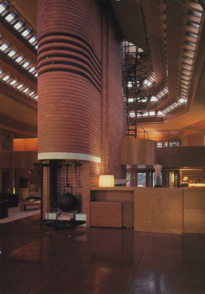 Interior view of Wingspread, featuring the central chimney. Text on the top on reverse reads: "The central chimney features five fireplaces." On the bottom reverse, below the Wingspread logo, it reads: "Wingspread, completed in 1939, was designed by Frank Lloyd Wright. Built as a residence for H.F. Johnson, Wingspread is now an international educational conference center maintained by The Johnson Foundation in Racine, Wisconsin."