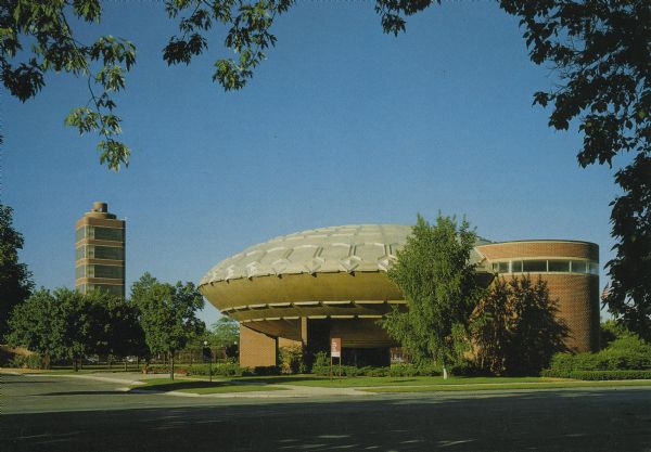 The SC Johnson Wax Golden Rondelle Theater was built for the 1964 World's Fair in New York. Afterwards the Theater was moved to Racine. The SC Johnson Research Tower can be seen in the distance. Text on the reverse reads: "The SC Johnson Wax Golden Rondelle Theater, located in Racine, Wisconsin, is used as the company's Guest Relations Center. Regularly Scheduled film and tour programs are available to the public free of charge. For information and reservations please call (414) 631-2154, Monday - Friday. Photo Courtesy SC Johnson Wax."