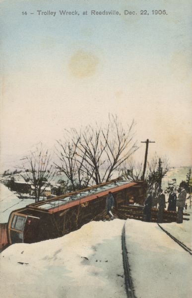 Text on front reads: "Trolley Wreck at Reedsville, Dec. 22, 1906." A streetcar has rolled onto its side, off of the tracks. Several people are looking at the damage. Snow is covering the ground.