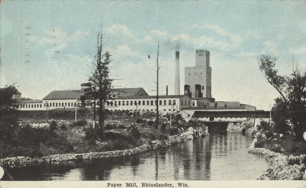 Text on front reads: "Paper Mill, Rhinelander, Wis." View of the Rhinelander Paper Mill looking up the outflow of the dam on the Wisconsin River that powers the mill. It was built in 1903 and has changed owners several times. Many additions have been added through the years.