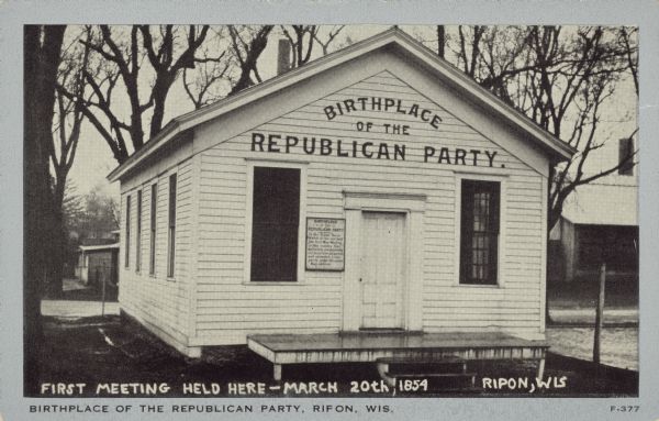 Text at foot reads: "Birthplace of the Republican Party, Ripon, Wis." Handwritten at foot of image: "First Meeting Held Here-March 20th, 1854. Ripon, Wis." The Little White Schoolhouse, the birthplace of the Republican Party in 1854. Surrounded by dwellings and trees, the schoolhouse has signs on it explaining its significance. It has been moved 4 times, the last in 1951. In 1974 it was declared a National Historic Landmark.