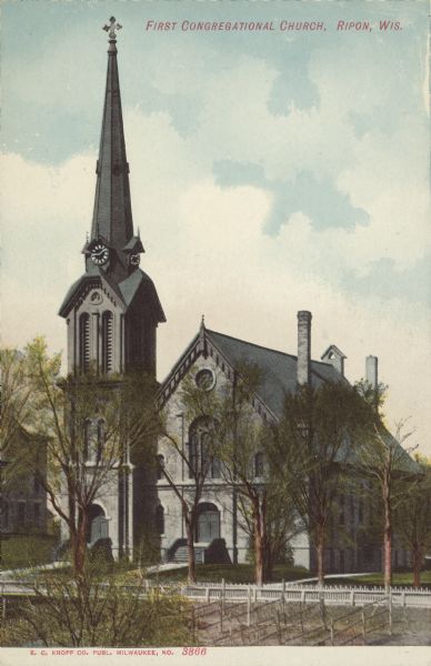 Text on front reads: "First Congregational Church. Ripon, Wis." The church was built in 1865 of limestone. It has a tall steeple with a bell and a clock and is surrounded by trees.