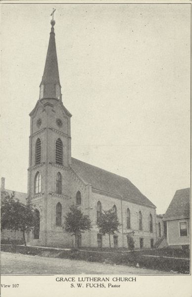 Text on front reads: "Grace Lutheran Church, S.W. Fuchs, Pastor." A brick Gothic Revival church with arched windows and a tall steeple. It was built in 1888 and demolished in 1984.
